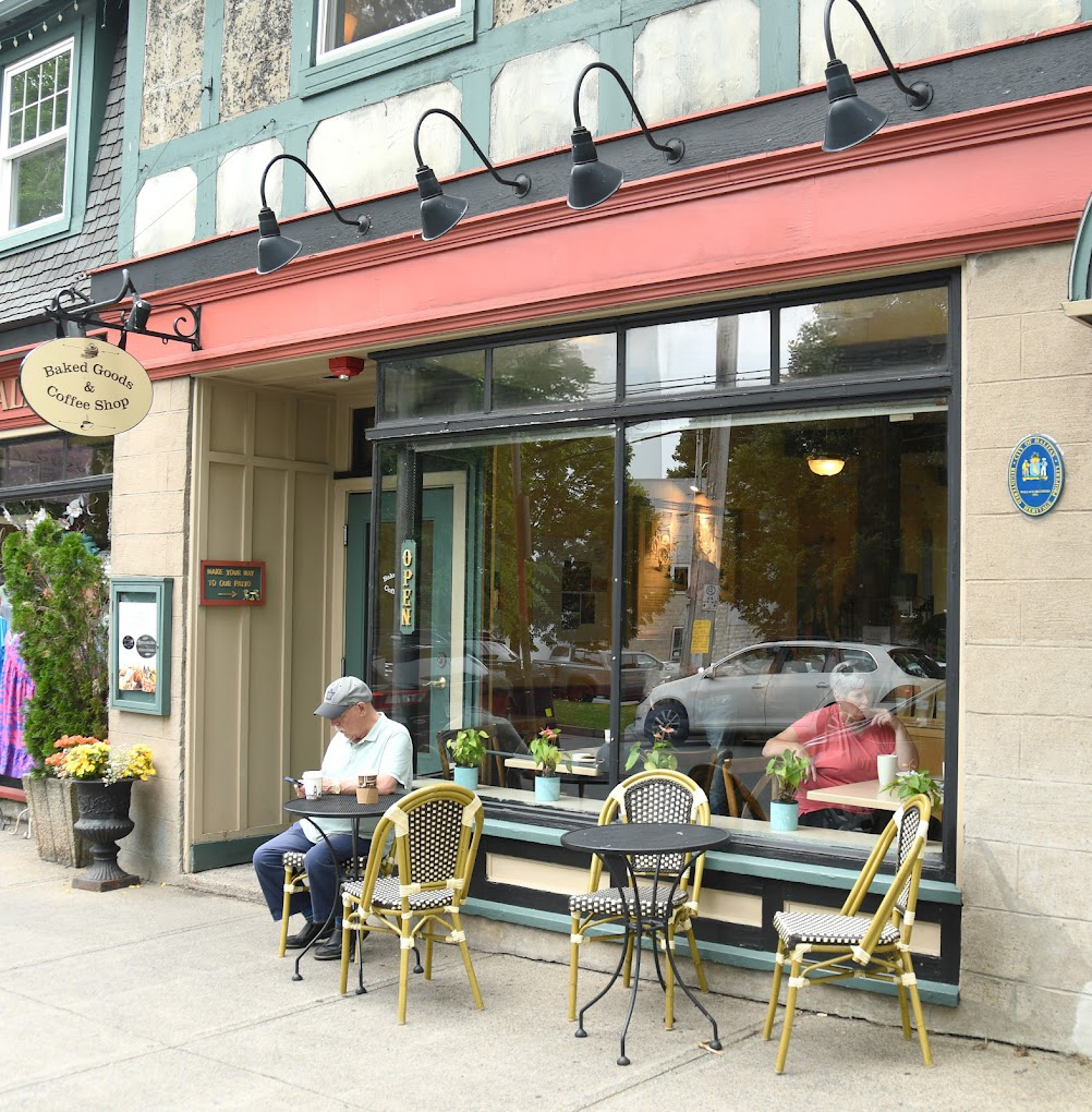 Customers relaxing at bistro tables in front of the café's window